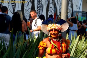 Mulher índia, vestida com trajes típicos em frente à Casa Brasil/ Eine Indio-Frau in traditioneller Kleidung vor dem Haus Brasilien/An indigenous woman in traditional clothing in front of the house Brazil